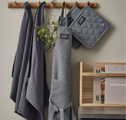 Pillivuyt köksset med grått förkläde, handdukar och grytlappar återvunnen textil