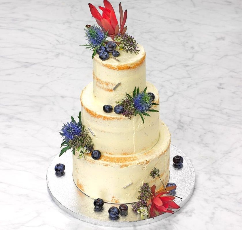 T�rta i tre v�ningar dekorerad med sm�rkr�m och blommor.