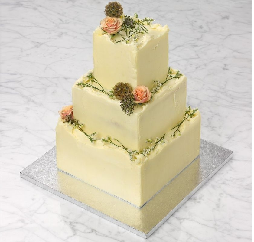 T�rta i 3 delar byggd av 3 fyrkantiga kakor med sm�rkr�moch blommor