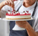 Konditor håller tårtfat med röd och vit tårta