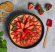 Chees cake med jordgubbar i springform och en rd skedformad mini-slickepott