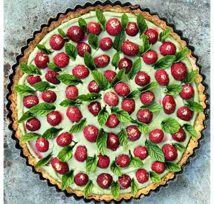 pajform med tart. Hallon, matchafyllning, blad och guld som dekoration