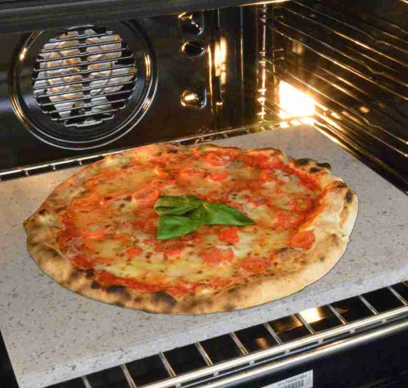 Pizzasten av lavasten i ugnen med pizza