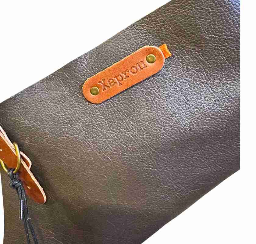 Detalj av l�dret med pr�glad logo p� skinnf�rkl�de kakaobrunt fr�n Xapron