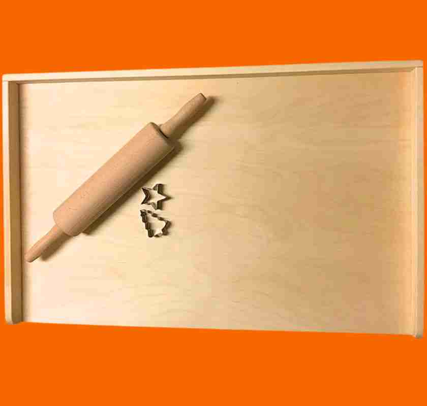 Bakbord i tr� med kavel och pepparkaksformar mot orange bakgrund