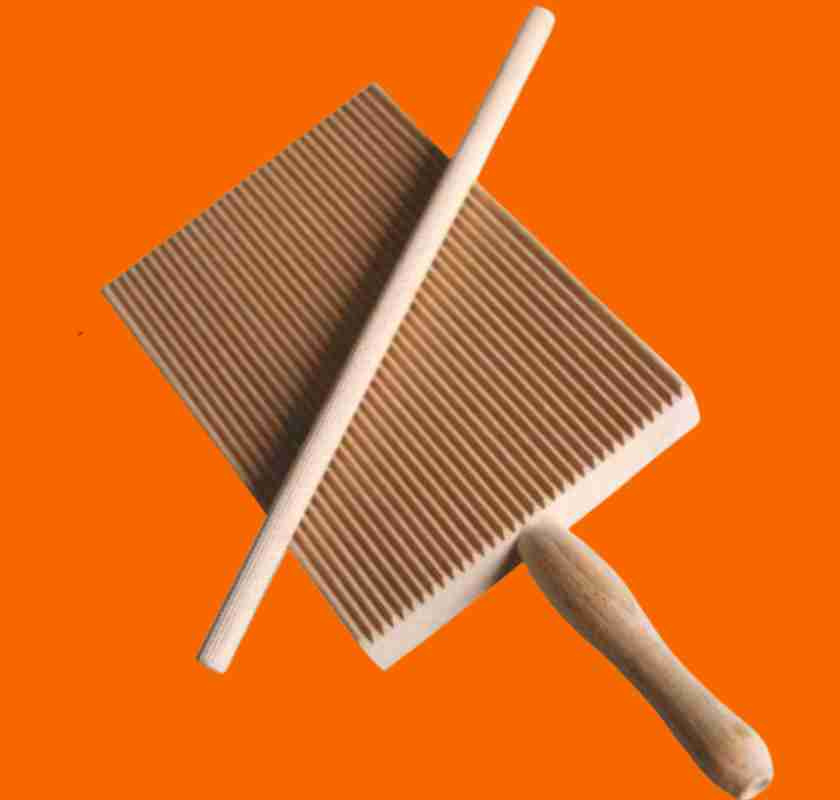 Garganelli- & Gnocchibr�da med pinne mot orange bakgrund