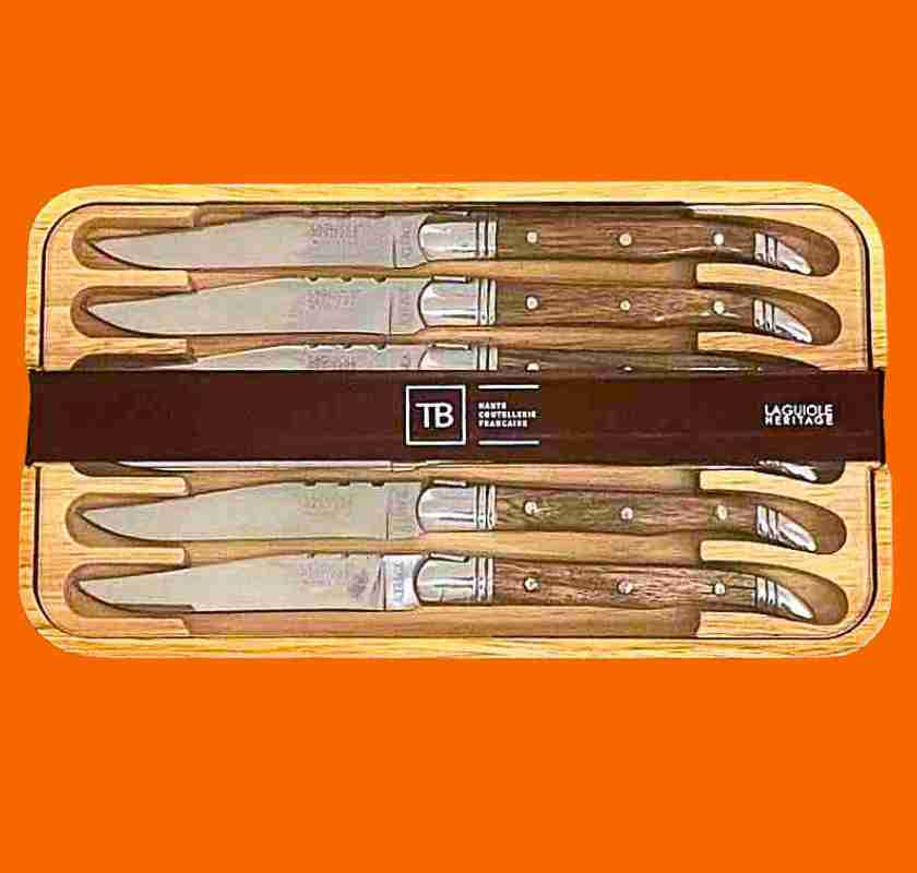 Laguiole K�ttknivar med handtag av tr� i ask mot orange bakgrund