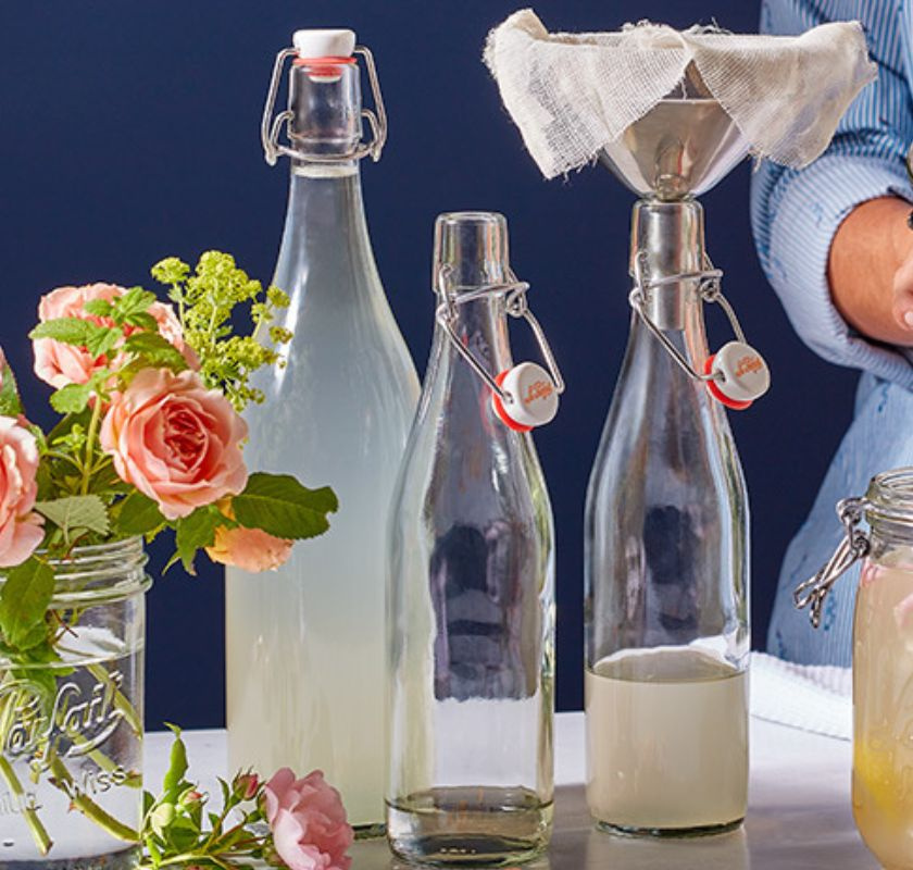 flera glasflaskor som fylls med tratt