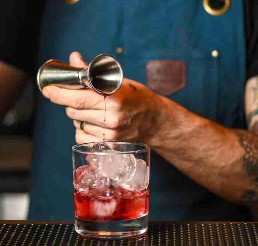 H�ller Campari i glas med en jigger Japanese style m�tglas f�r drinkar