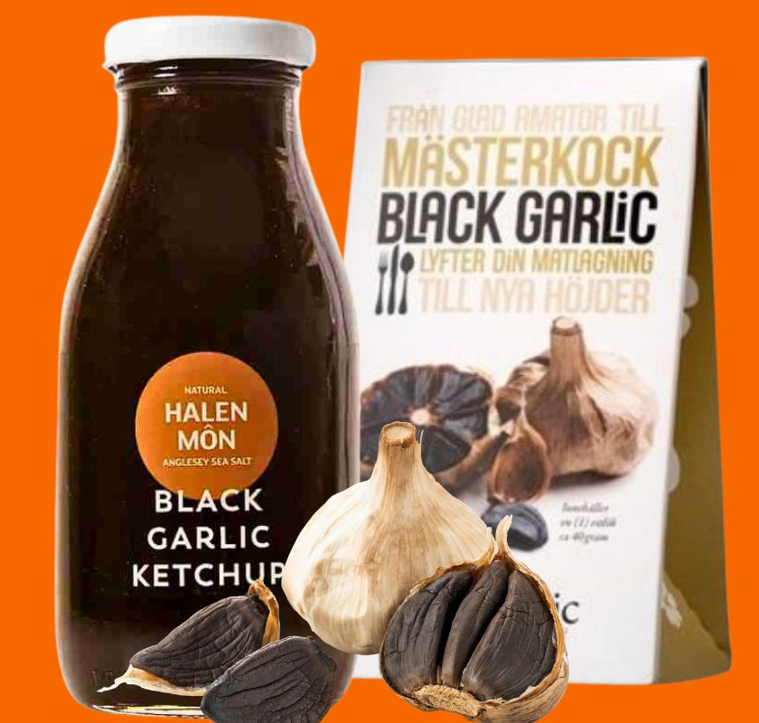 En flaska svart vitlök ketchup och en förpackning med svart vitlök bredvid hela vitlöksklyftor. Produkten marknadsförs för matlagning.