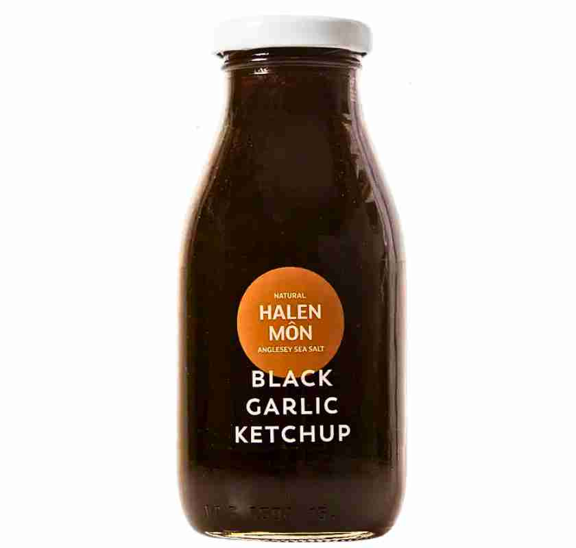 Glasflaska med svart vitlök ketchup, märkt med texten 