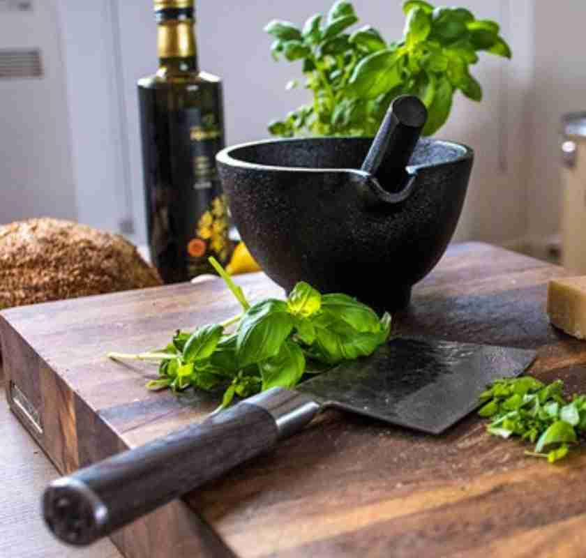 Mortel i gjutj�rn p� sk�rbr�da med kniv och basilika 