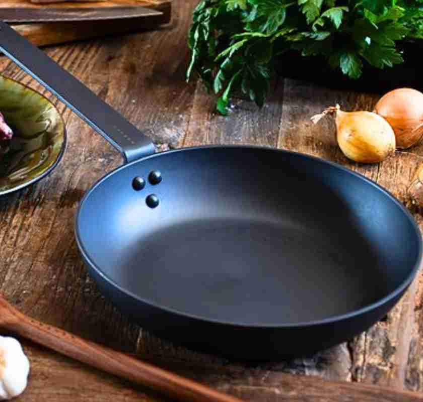 Stekpanna i kolst�l Satake p� bord med ingredienser