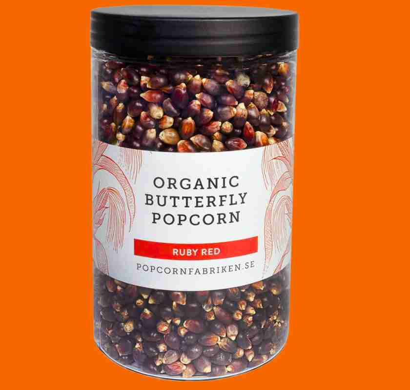 R�da popcorn red organic butterfly Ruby Red fr�n Popcornfabriken� burk mot orange bakgrund