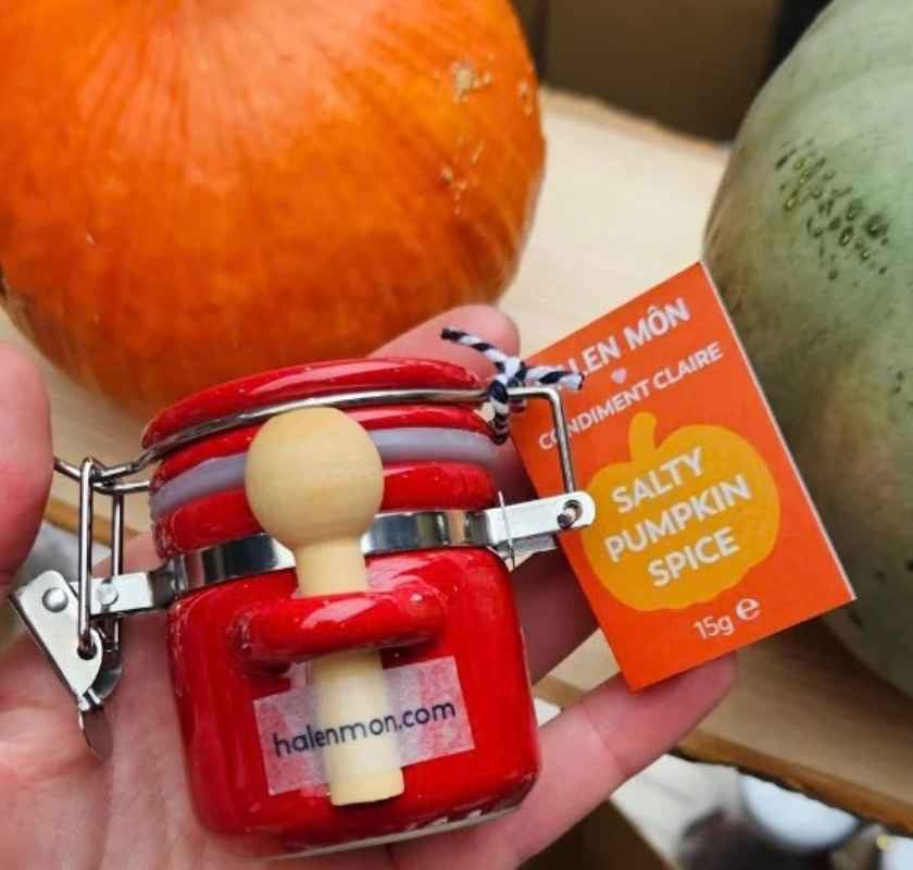  Halen Môn Salty Pumpin Spice - halloweensalt i handen. Pumpor i bakgrunden